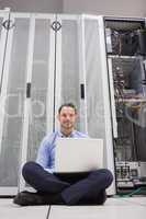Man sitting in front of servers with his laptop