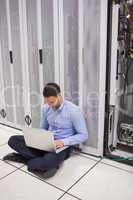 Technician looking at his laptop while doing maintenance on serv
