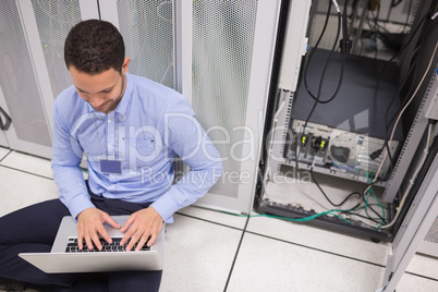 Technician typing on the laptop in front of server