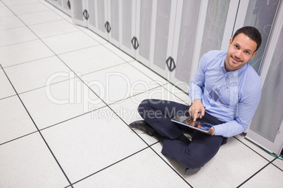 Man using tablet pc sitting beside servers