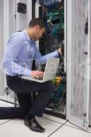 Man fixing wires while doing maintenance in data center