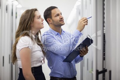 Technicians with clipboard looking at servers