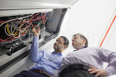 Technicians checking wires of server