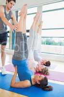 Trainer helping woman at yoga class