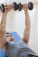 Man lifiting dumbbells while lying