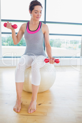 Woman lifting weights on exercise ball