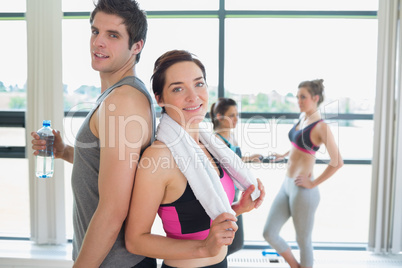 Man and woman standing back to back at the gym