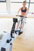 Woman sitting at the row machine pulling