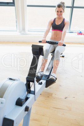 Woman sitting at the row machine pulling and smiling