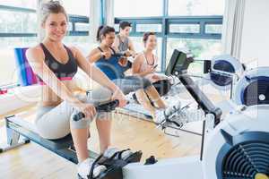 Smiling woman on rowing machine with others
