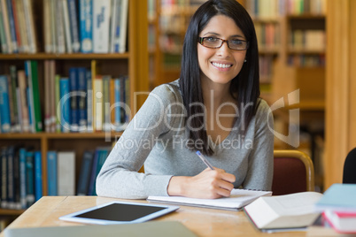 Smiling woman taking notes while doing research