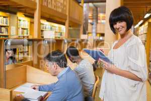 Smiling woman holding a tablet pc in the library