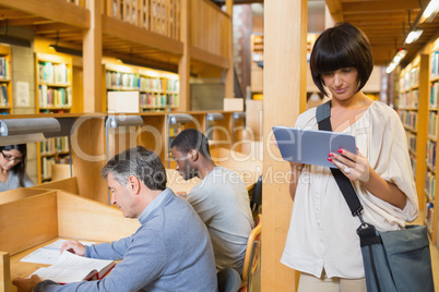 Woman looking at her tablet pc while other people are reading