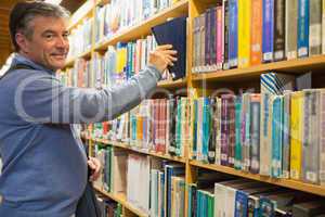 Smiling man taking a book from shelves