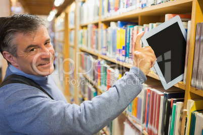 Smiling man taking a tablet pc from shelves