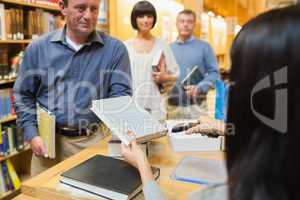 Librarian handing book to man