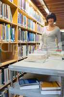 Smiling librarian pushing book trolley