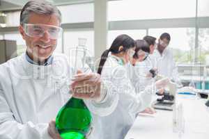 Smiling chemist raising a liquid