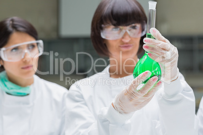 Female chemists viewing  green liquid