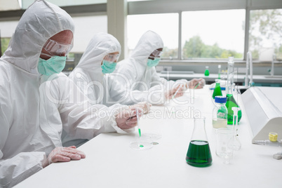 Three chemists working in protective suits