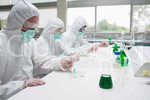 Three chemists working in protective suits