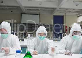 Chemists in protective suits adding liquid to petri dishes