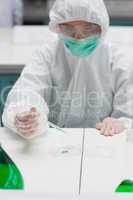 Woman in protective gear working with green liquid