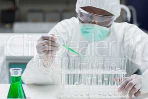 Chemist filling test tubes with green liquid