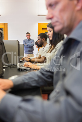 Teacher standing and smiling in computer class