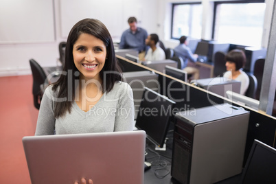 Woman using  laptop while others working at computers