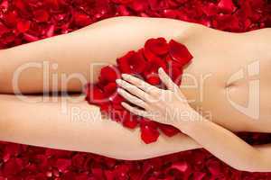 Beautiful body of woman against petals of red roses