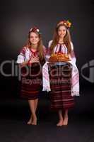 Young women in ukrainian clothes, with garland and round loaf on