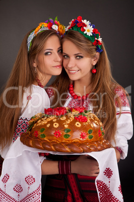 Young women in ukrainian clothes, with garland and round loaf