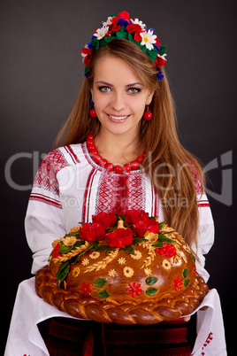 Young woman in ukrainian clothes, with garland and round loaf