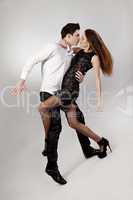 Beautiful young couple are dancing on grey