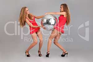 Two girls twins with glitterball on grey