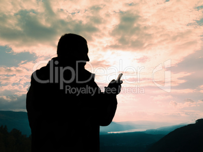 Silhouette of the man with a mobile phone against a sunset