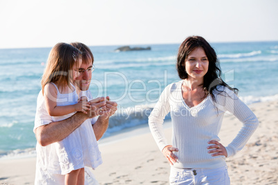 glückliche junge familie mit kleiner Tochter am Strand am wasse