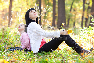 beautiful young mother and her daughter looking up in the autumn