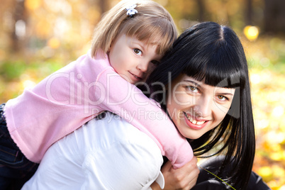 beautiful young mother holding her daughter on back