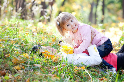 beautiful young mother and her daughter lying on the autumn leav