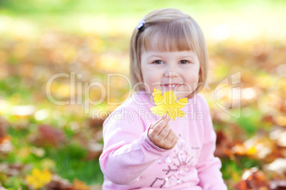 portrait of a beautiful little girl holding a maple leaf in his