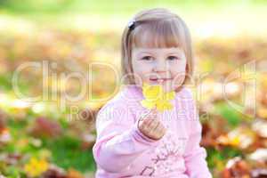 portrait of a beautiful little girl holding a maple leaf in his