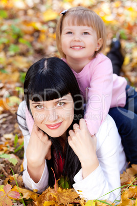 beautiful young mother and her daughter lying on the autumn leav