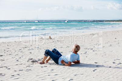 Junger mann entspannt am Strand am Wasser im Sommer