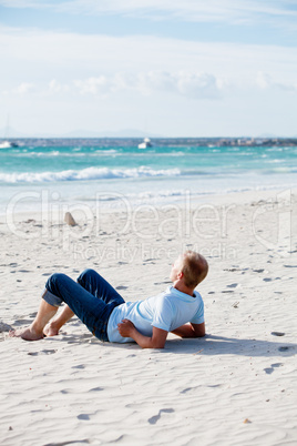 Junger mann entspannt am Strand am Wasser im Sommer