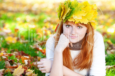 young redhead teenager woman in a wreath of maple leaves lying o