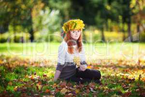 young redhead teenager woman in a wreath of maple leaves sitting