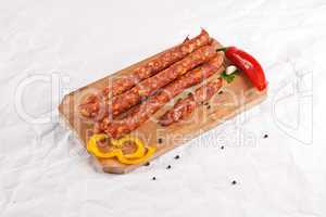 Wooden chopping board with sausages and spices