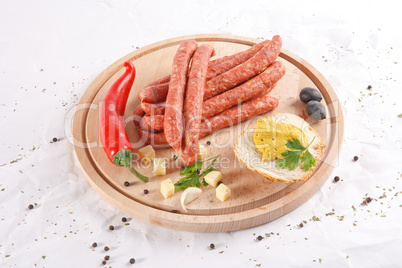 Wooden chopping board with sausages, cheese, bread